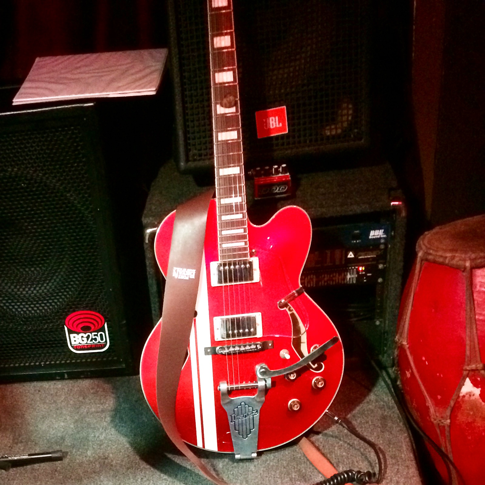 Ibanez semi-hollow body electric guitar plugged in an amplifier and leaning against a speaker. 