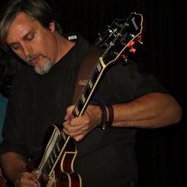 Man playing an Ibanez hollow-body electric guitar