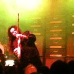 Yngwie Malmsteen playing live on stage with stacks of Marshall amplifiers behind him. 