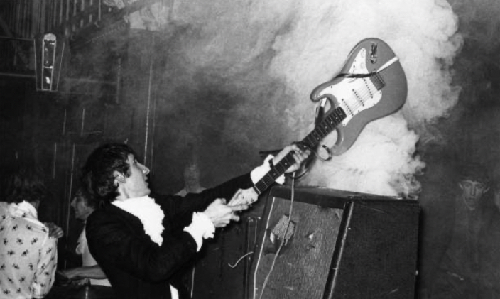 Pete Townshend smashing his guitar over an amplifier 