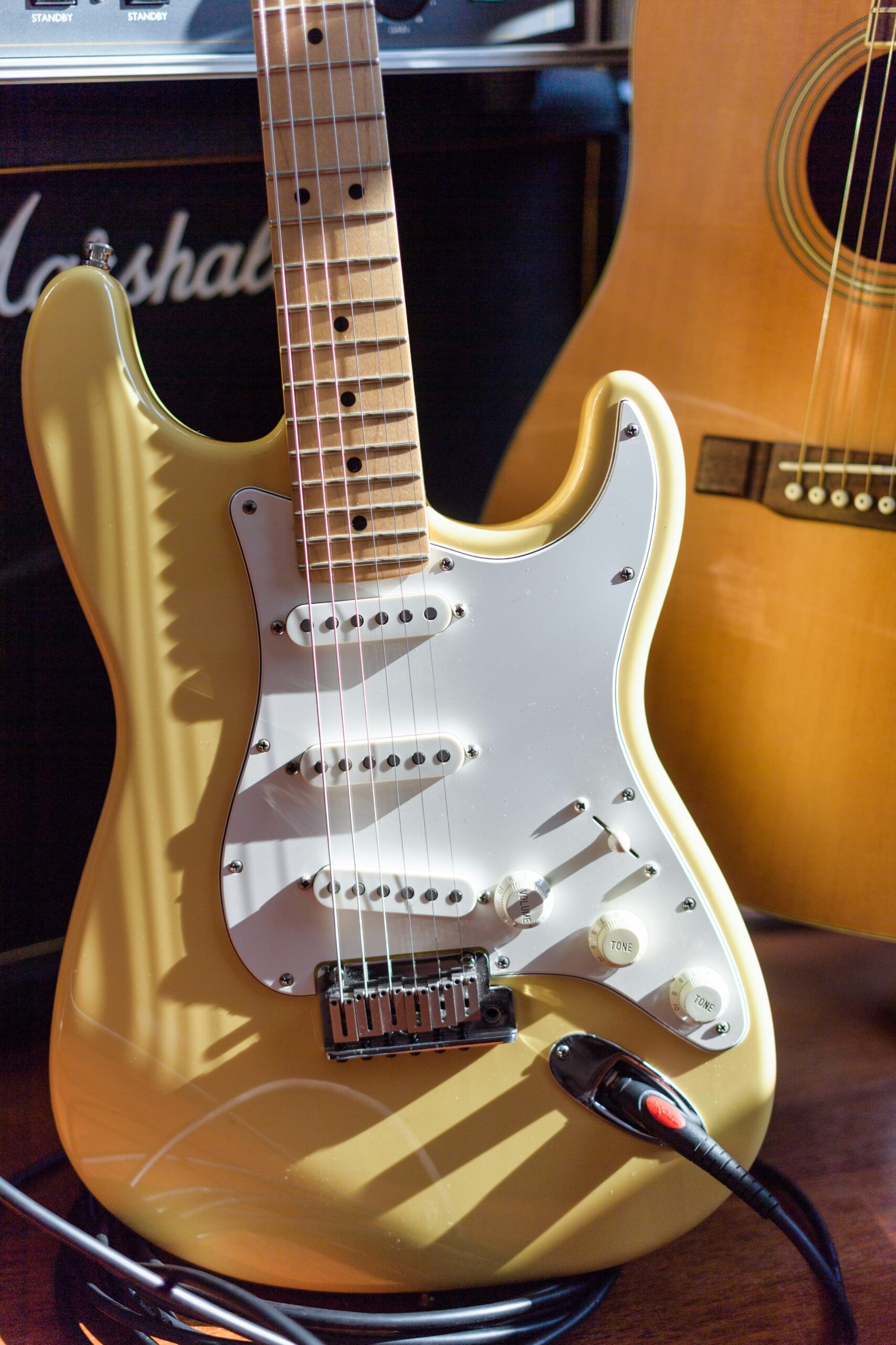 A fender strat with a maple neck leaning on a Marshall amplifier 