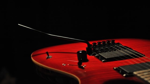 Close-up of a red guitar with a black whammy bar