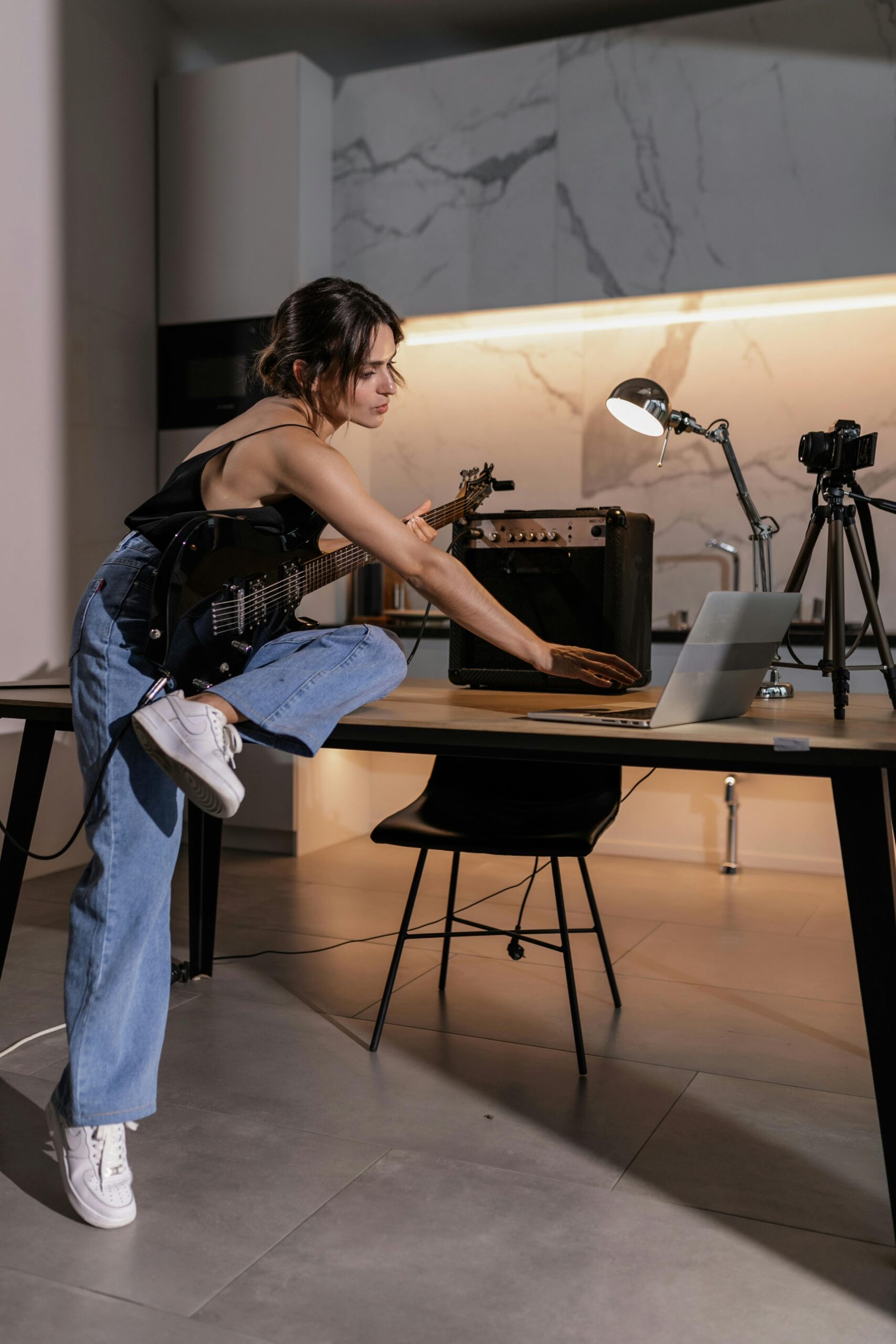 Female guitarist playing through a mini-amp inside an office setting.