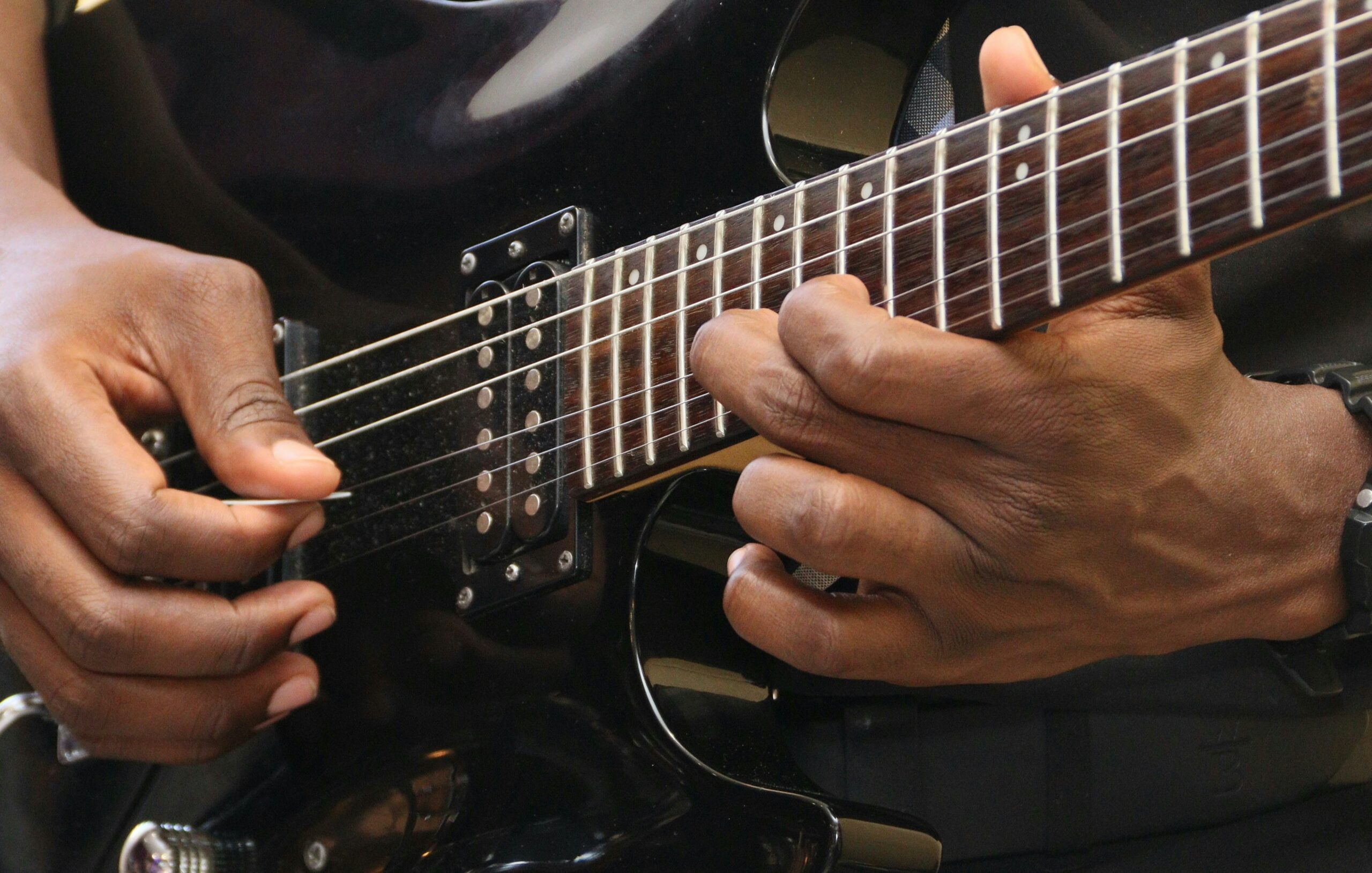 Guitarist bending a string on electric guitar.